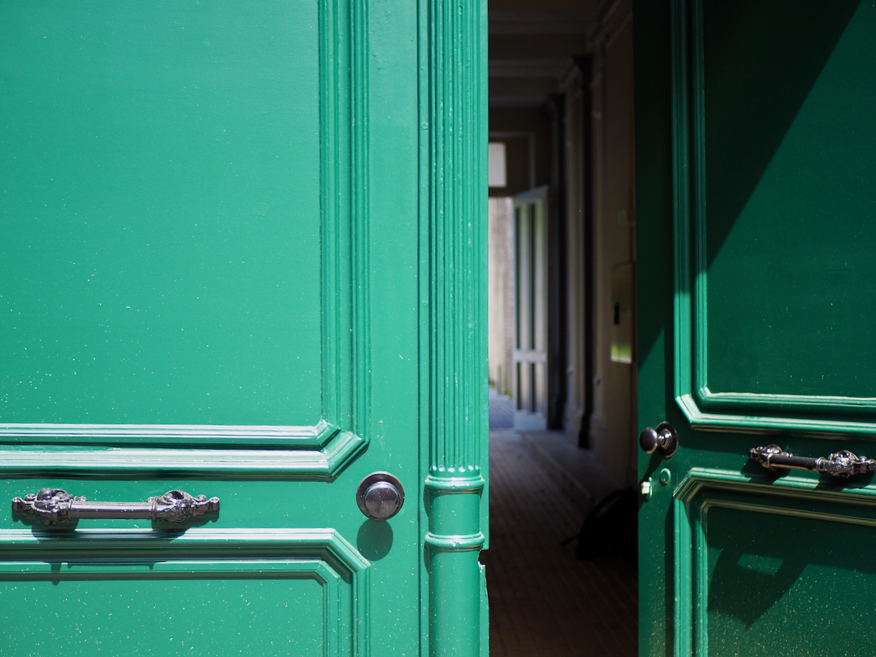 An old green door with two wings, one open.