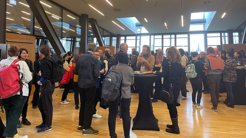 Participants chatting around cocktail tables.