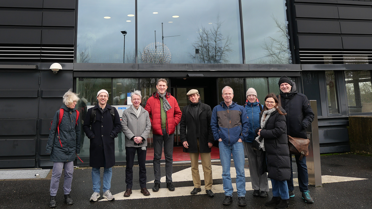 Group photo of nine people in winter clothes outdoors.