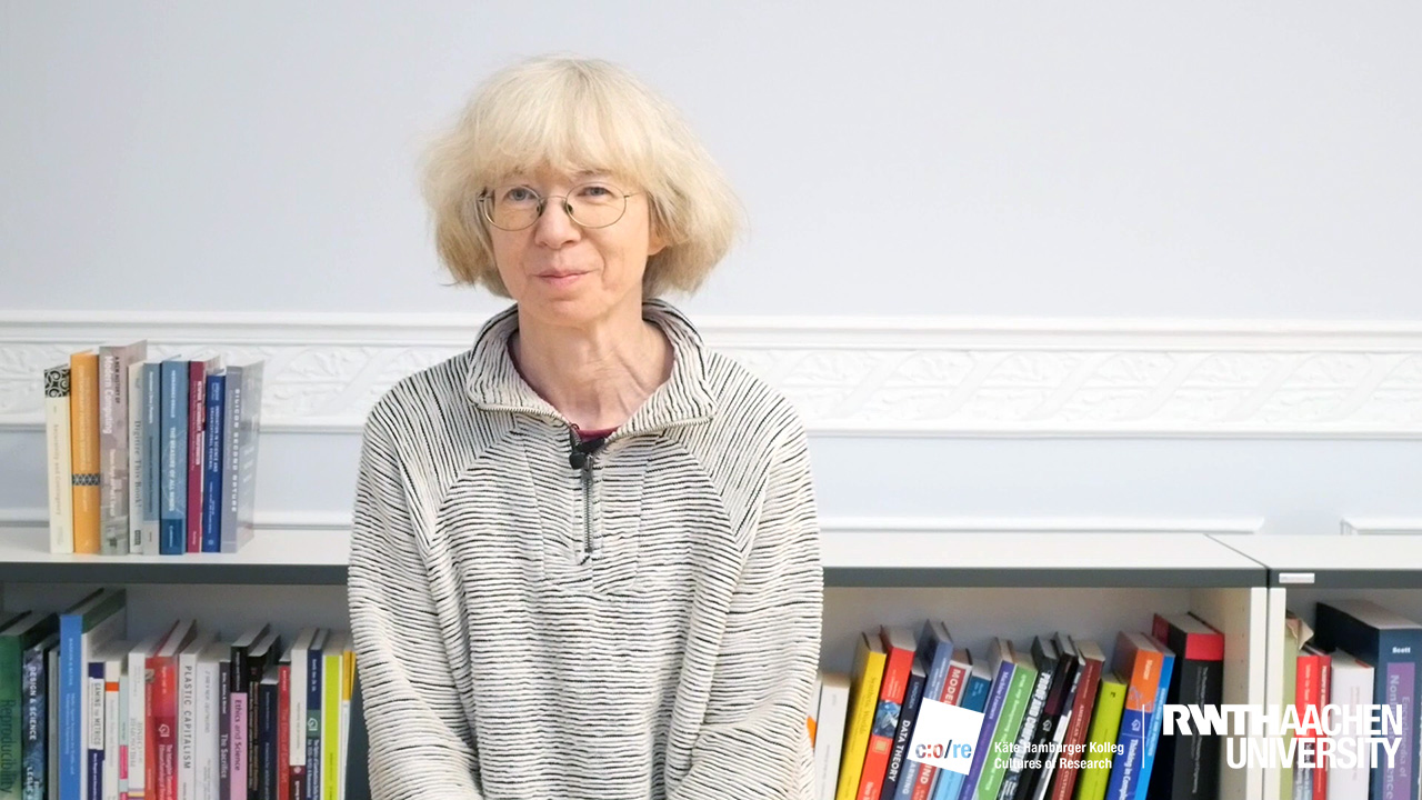 Woman sitting in front of a bookshelf.
