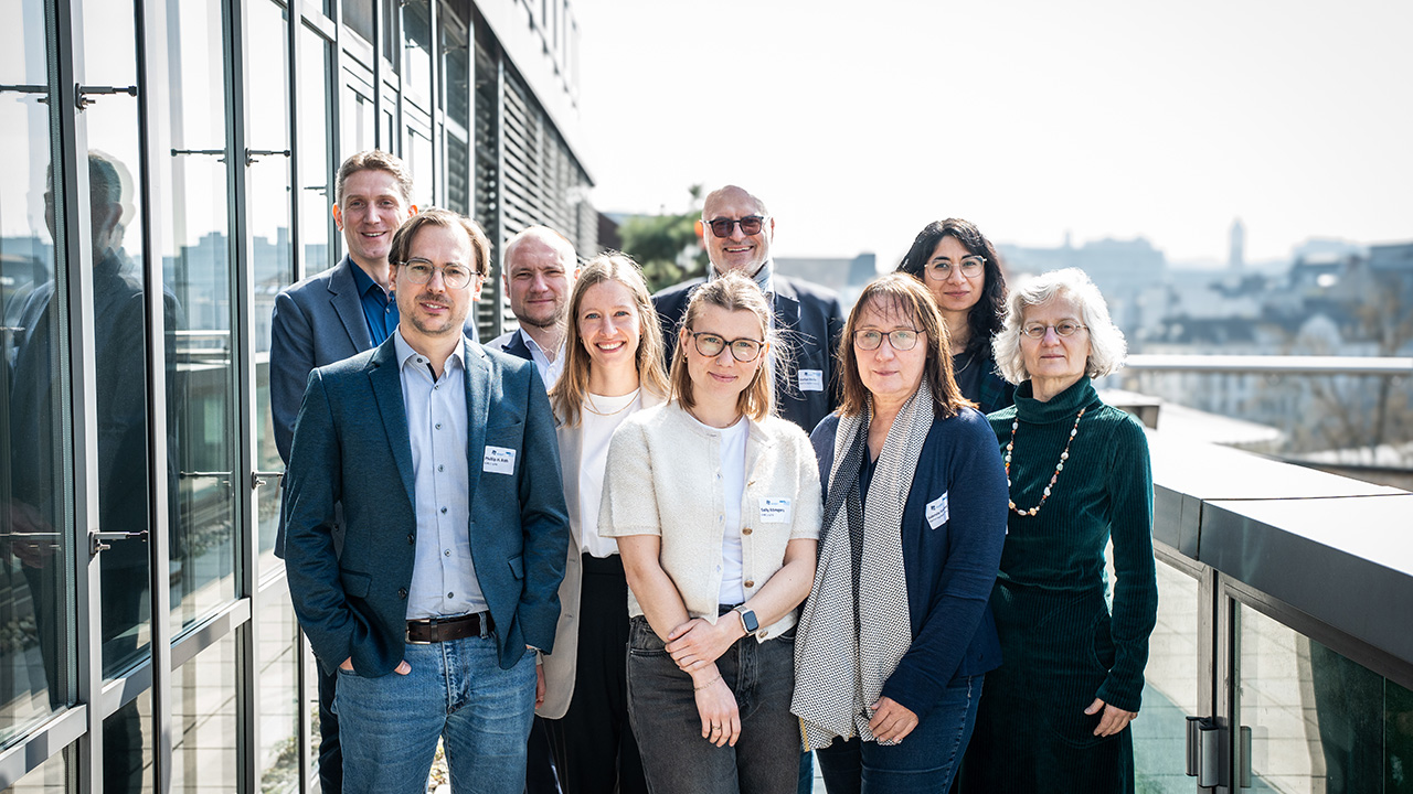 Group photo of nine people posing together at a terrace.