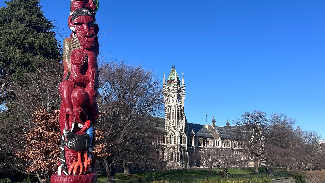 A red, tall sculpture in front of the building of the main building of the University of Otago in Dunedin, New Zealand.